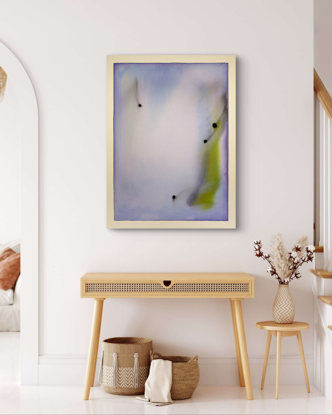 Abstract artwork on a wall above a wooden console table with decorative items.