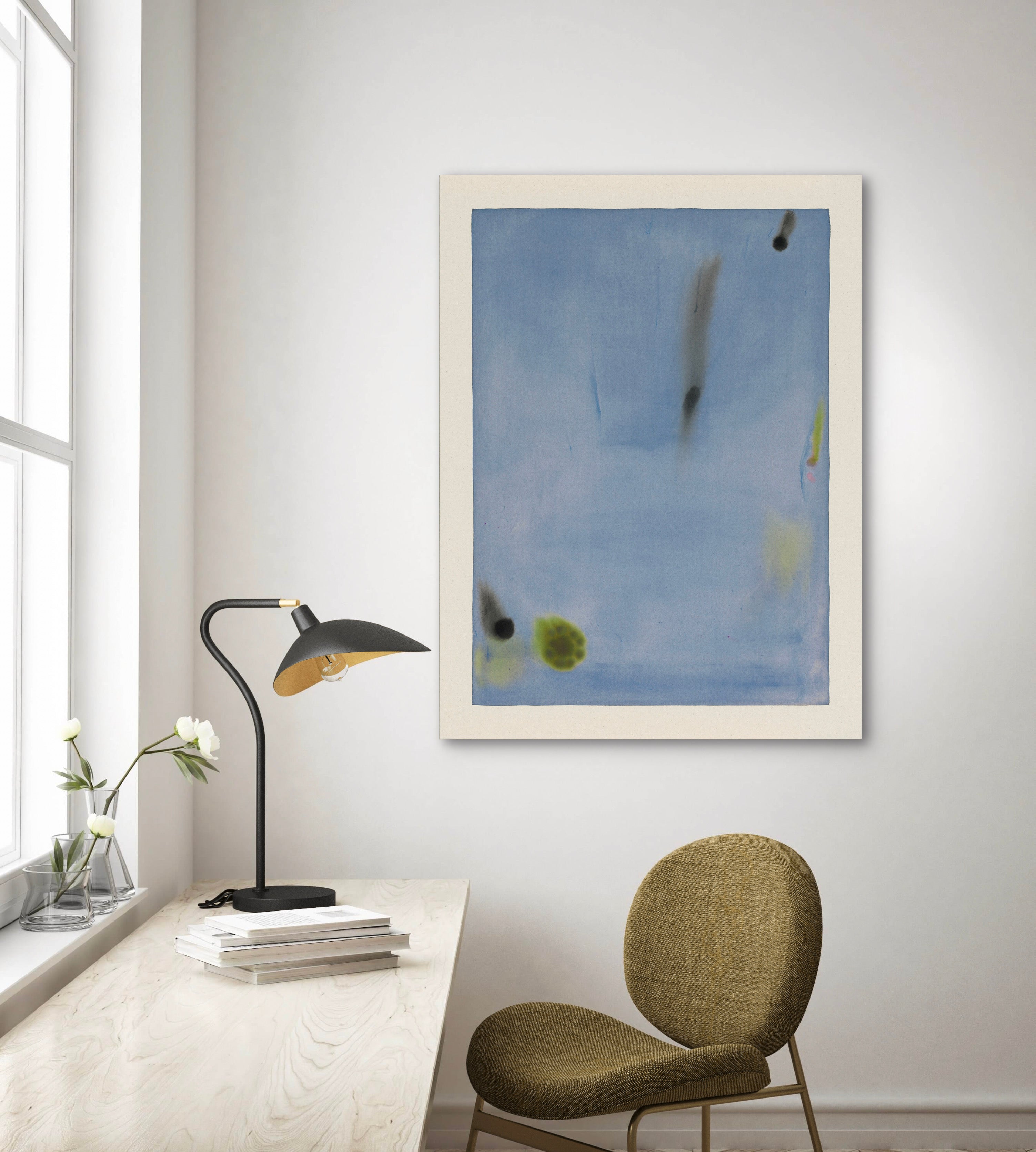 Abstract artwork on a wall above a desk with a lamp and chair.
