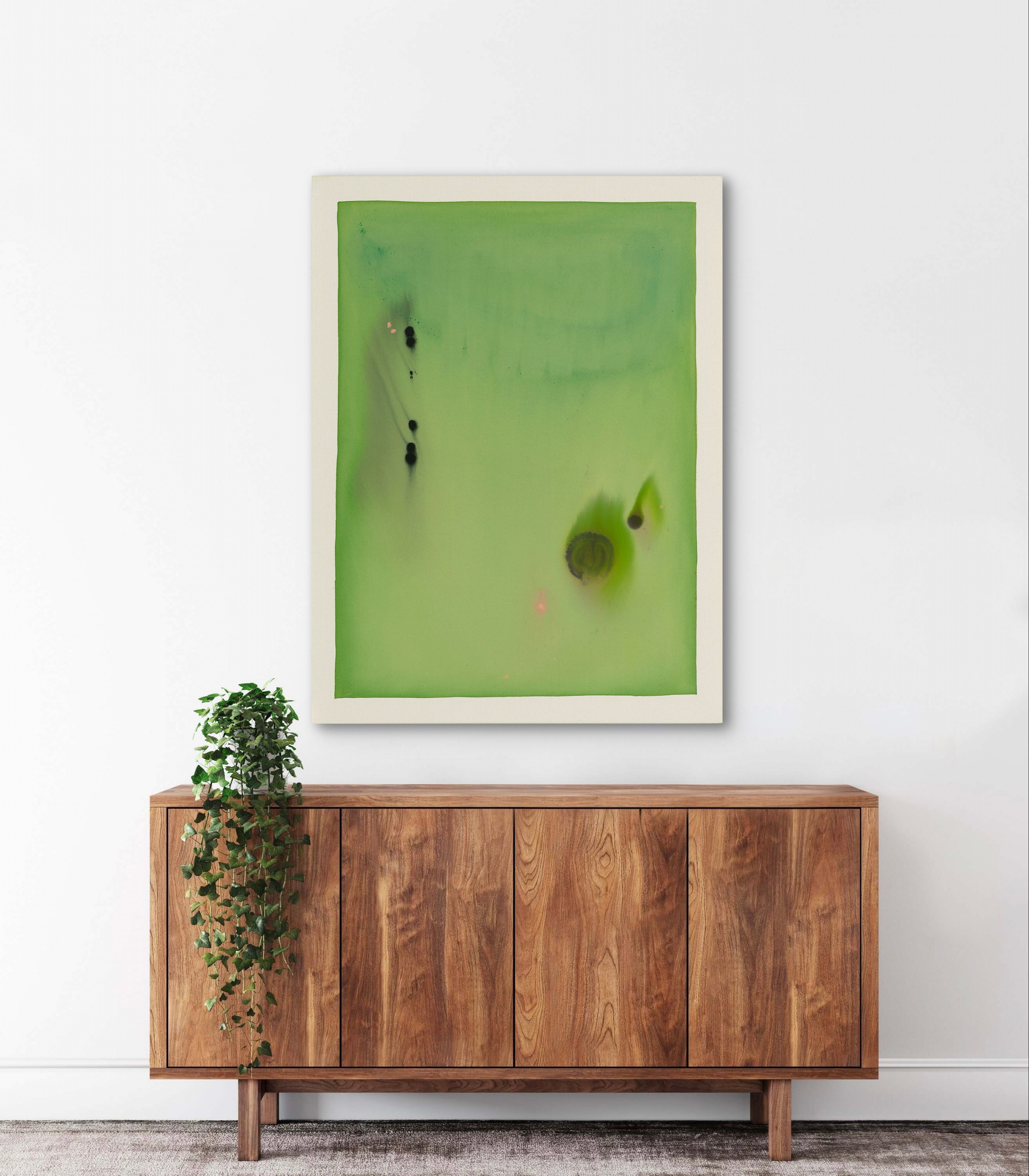 Abstract green artwork on a white wall above a wooden cabinet with a plant.