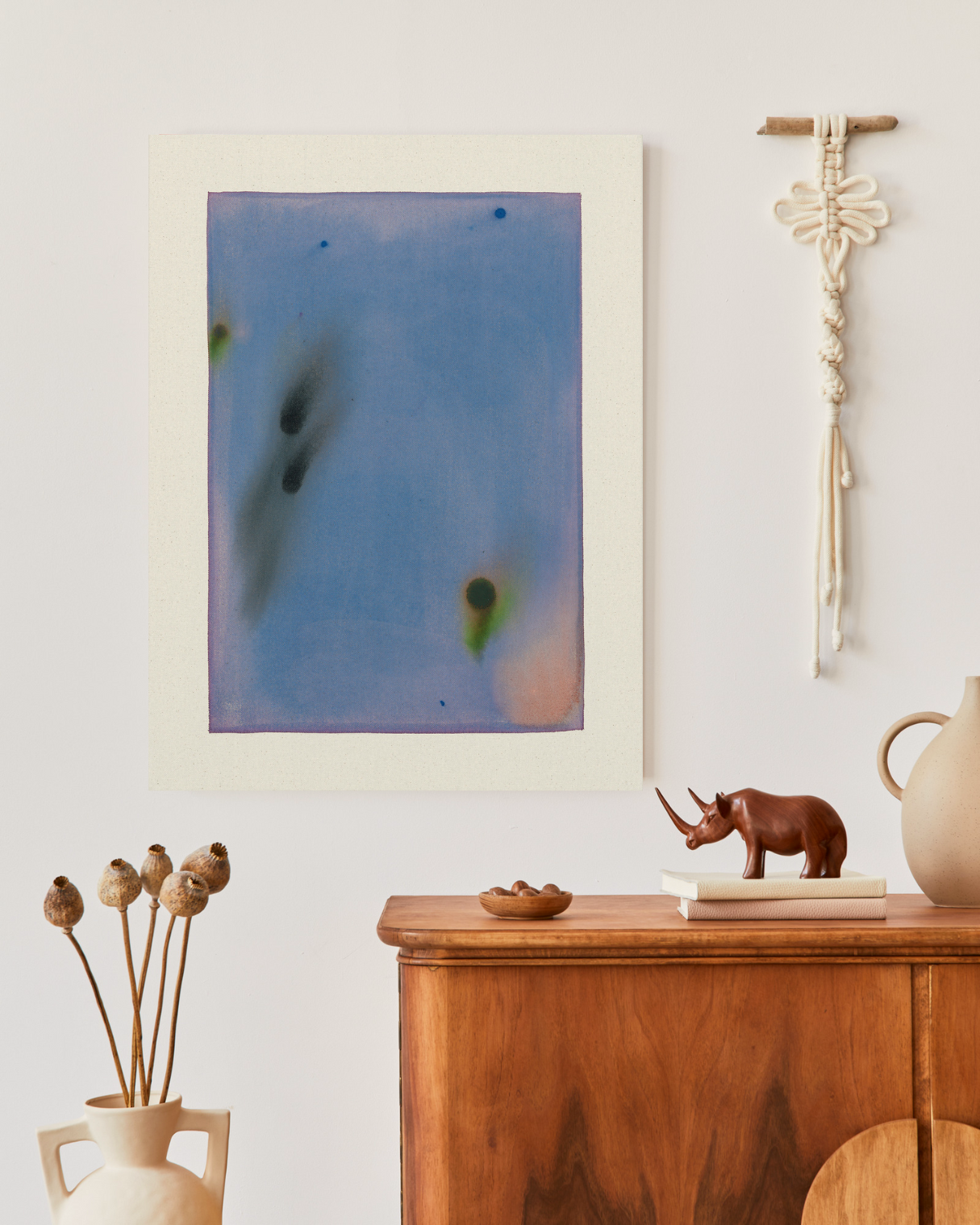 Abstract art on a wall above a wooden cabinet with decorative items.