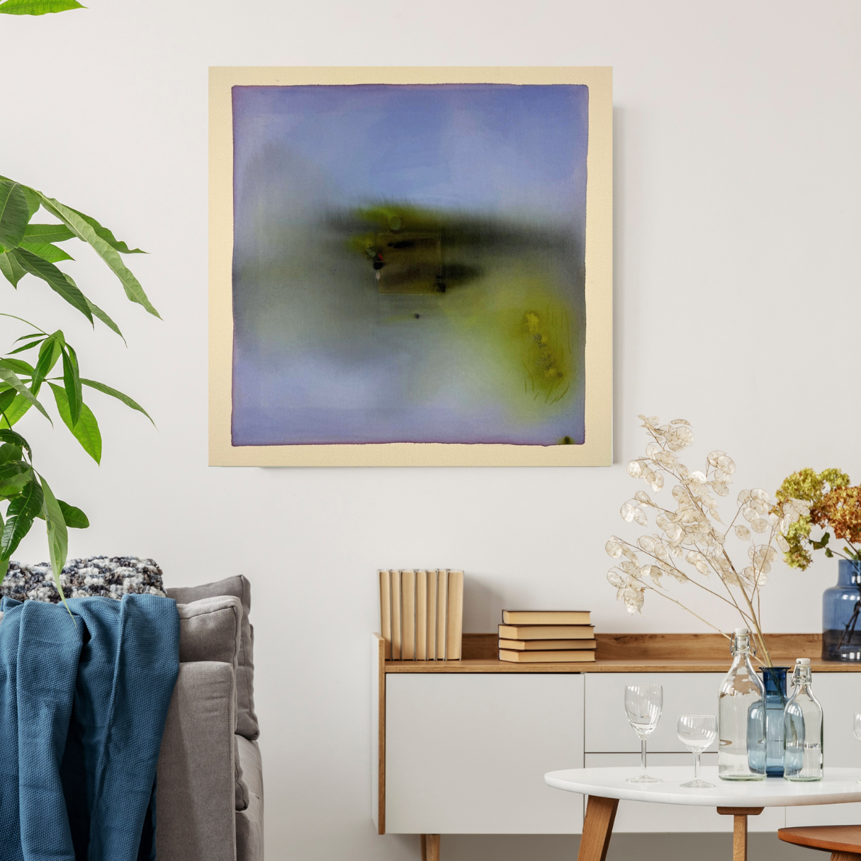Abstract art piece on a wall above a sofa with decorative items on a side table.